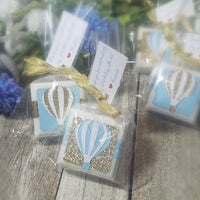 Baby shower favor soaps with hot air balloons design on the packaging blue and gold with ribbons and a text tag hung from the ribbon with custom wording
